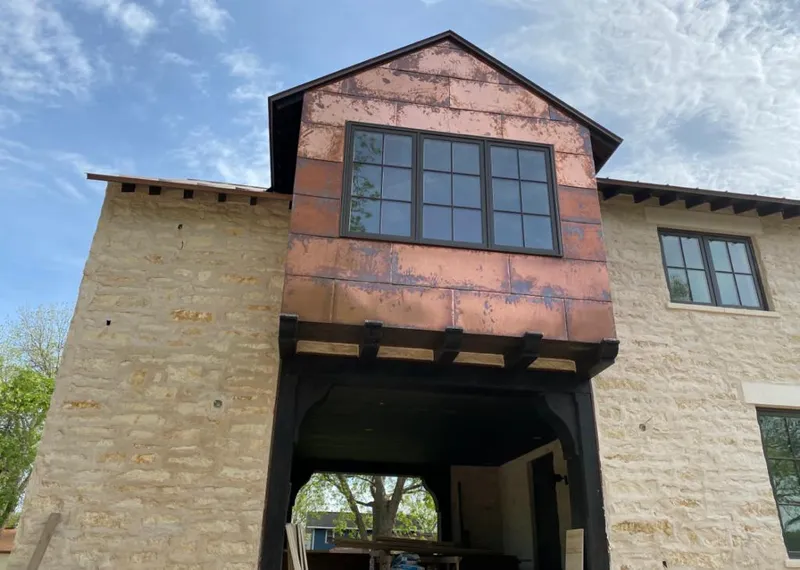 Copper metal panel facade on a stone building for Roof Repair in Iowa Colony
